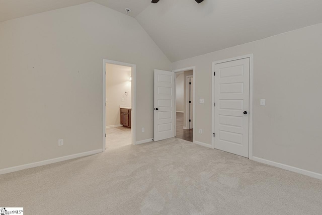 unfurnished bedroom with ensuite bath, vaulted ceiling, a closet, ceiling fan, and light carpet