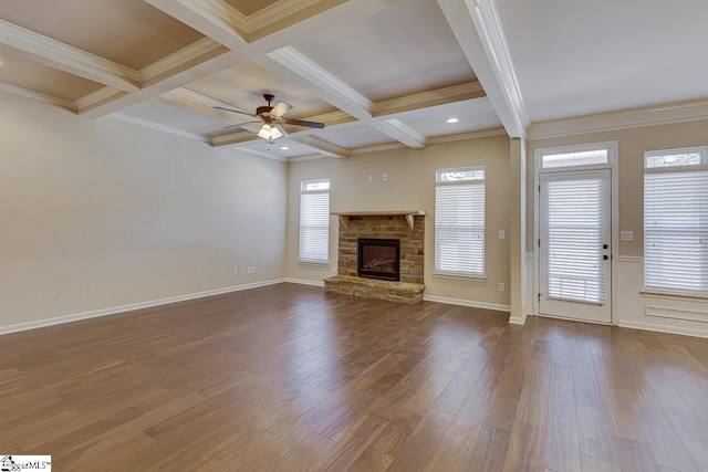 unfurnished living room with beamed ceiling, ornamental molding, ceiling fan, coffered ceiling, and a stone fireplace