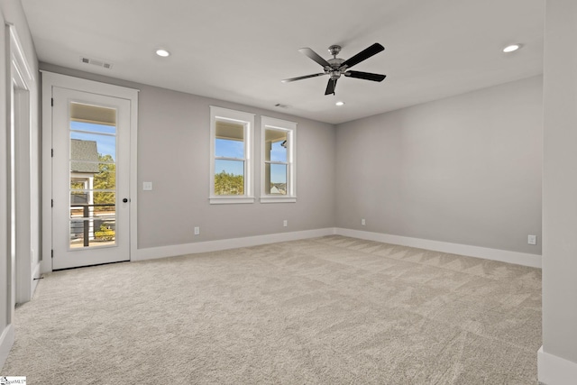 empty room with ceiling fan, a healthy amount of sunlight, and light carpet