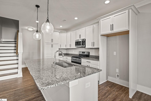 kitchen with pendant lighting, stainless steel appliances, an island with sink, white cabinetry, and sink