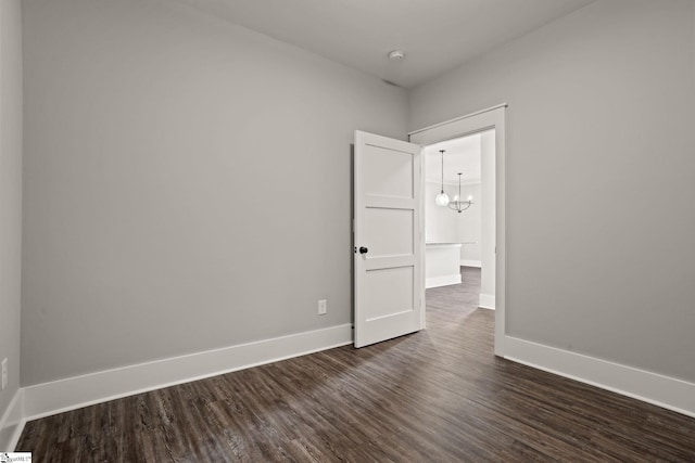 empty room with an inviting chandelier and dark hardwood / wood-style floors