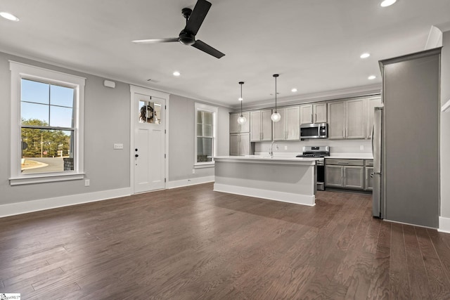 kitchen with appliances with stainless steel finishes, hanging light fixtures, a center island with sink, gray cabinetry, and dark wood-type flooring