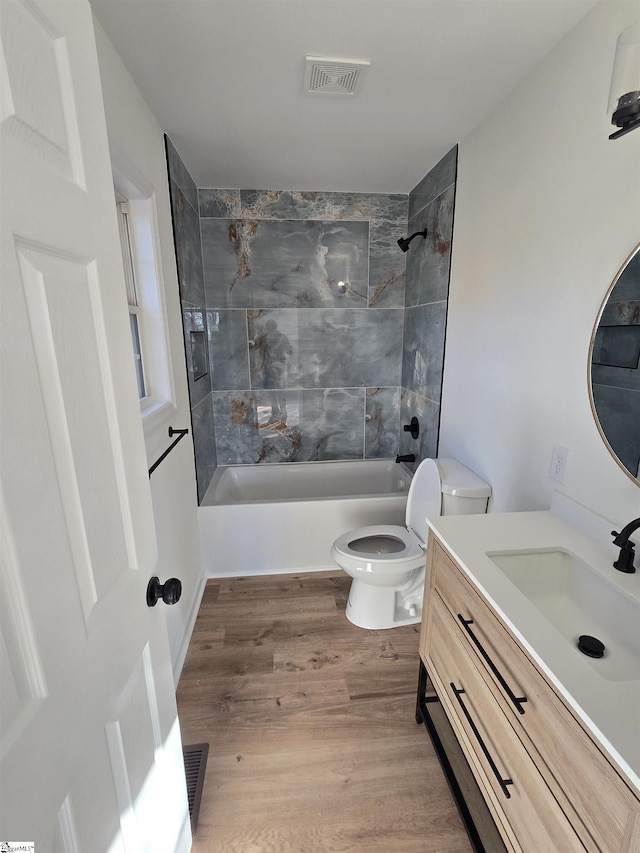 full bathroom featuring toilet, vanity, tiled shower / bath combo, and wood-type flooring