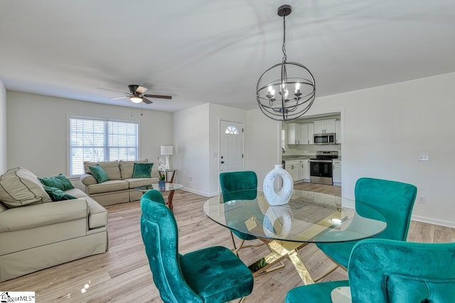 dining space with ceiling fan with notable chandelier and light wood-type flooring