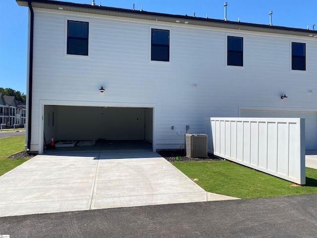 rear view of house featuring central AC unit and a garage