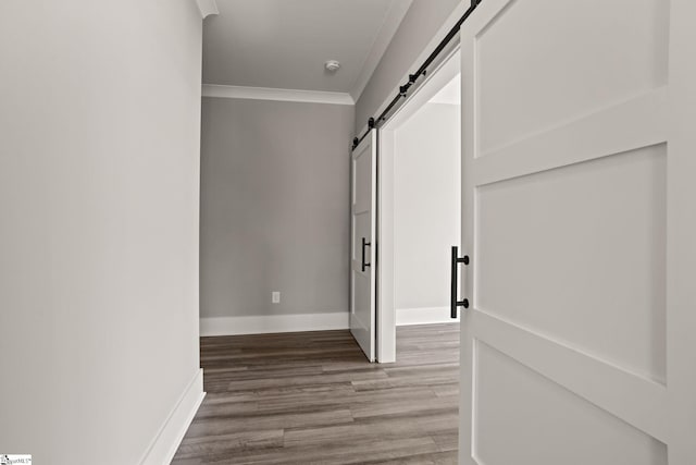 hall with hardwood / wood-style flooring, ornamental molding, and a barn door