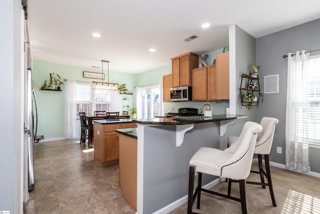 kitchen with kitchen peninsula, a center island, hanging light fixtures, electric range oven, and dark stone countertops