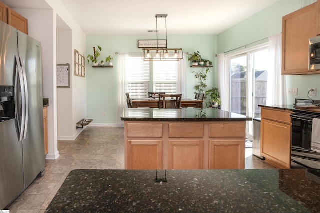 kitchen featuring a center island, hanging light fixtures, a notable chandelier, dark stone counters, and appliances with stainless steel finishes