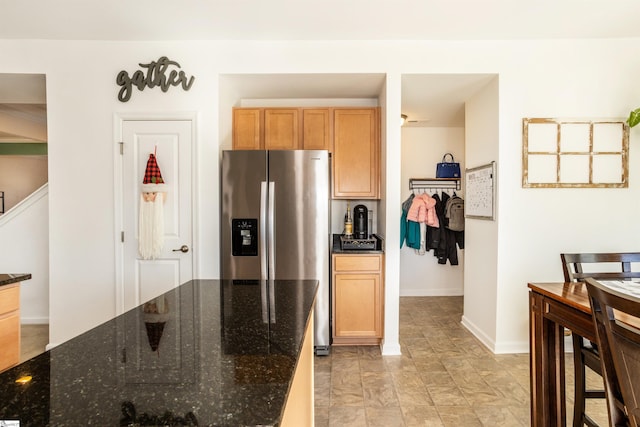 kitchen with dark stone counters and stainless steel refrigerator with ice dispenser