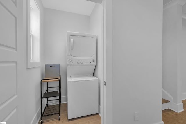 clothes washing area featuring light hardwood / wood-style flooring and stacked washer / dryer