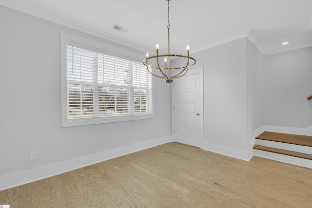 empty room featuring light hardwood / wood-style flooring, an inviting chandelier, and crown molding