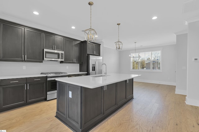 kitchen with light hardwood / wood-style flooring, decorative light fixtures, stainless steel appliances, a center island with sink, and sink