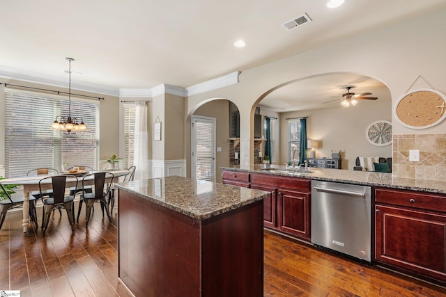 kitchen featuring dishwasher, hanging light fixtures, a kitchen island, ceiling fan with notable chandelier, and stone counters