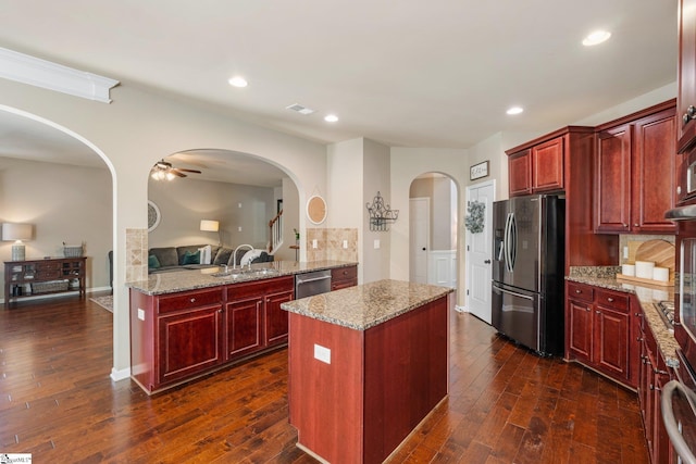 kitchen with appliances with stainless steel finishes, a center island, backsplash, and light stone countertops