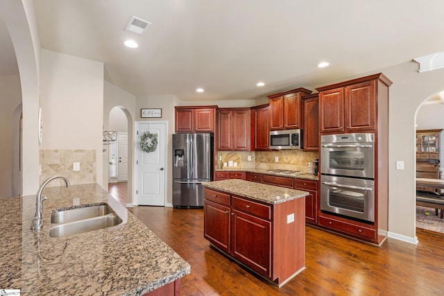 kitchen featuring sink, kitchen peninsula, decorative backsplash, light stone countertops, and appliances with stainless steel finishes