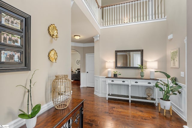 living room featuring a towering ceiling, ornamental molding, and dark hardwood / wood-style floors