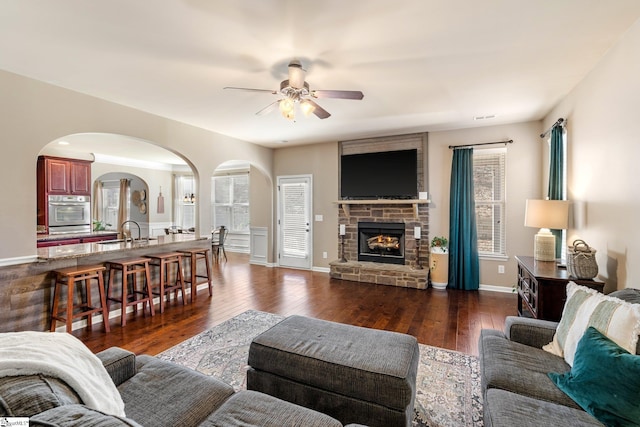 living room with ceiling fan, dark hardwood / wood-style floors, sink, and a fireplace