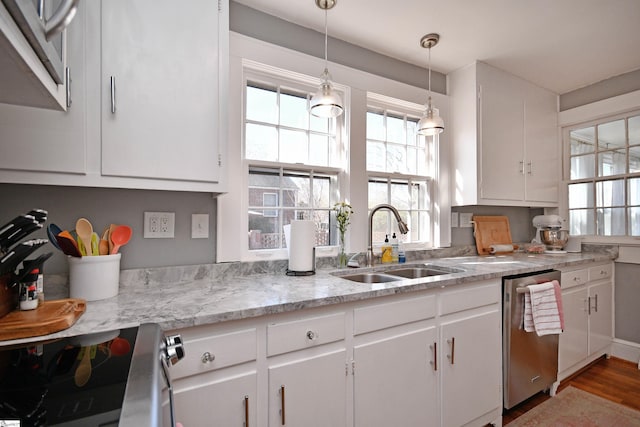 kitchen featuring stainless steel appliances, hanging light fixtures, light stone countertops, sink, and white cabinetry