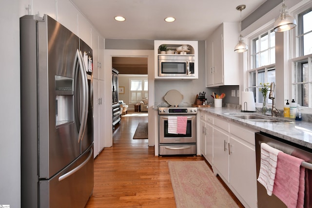 kitchen featuring stainless steel appliances, white cabinets, hanging light fixtures, and sink