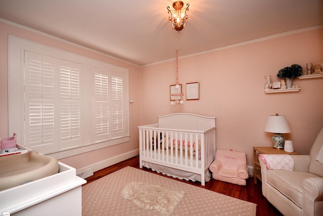 bedroom with a nursery area, crown molding, and dark hardwood / wood-style floors