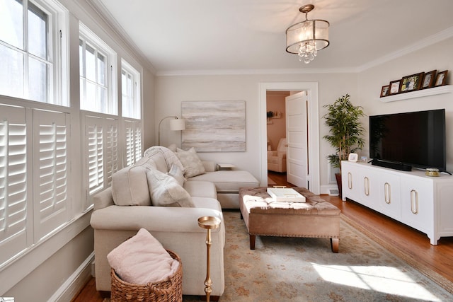 living room featuring wood-type flooring, crown molding, and a chandelier