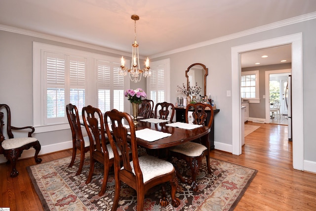 dining room with an inviting chandelier, light wood-type flooring, and crown molding