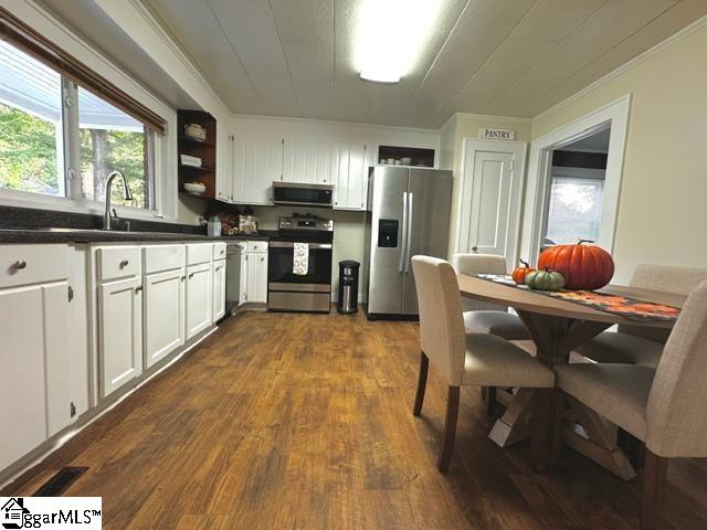 kitchen featuring stainless steel appliances, crown molding, dark wood-type flooring, white cabinets, and sink