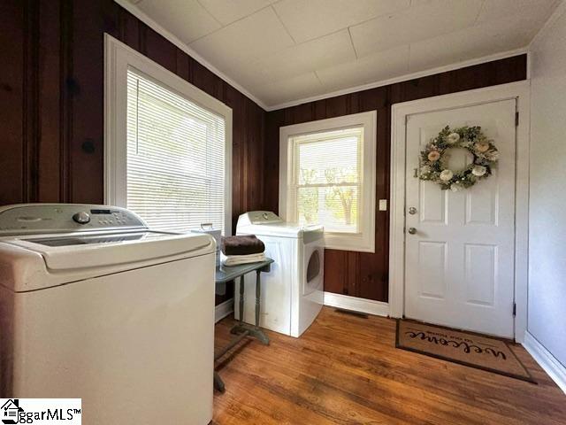 laundry room featuring independent washer and dryer, wood walls, crown molding, and wood-type flooring