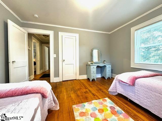 bedroom with ornamental molding and dark wood-type flooring