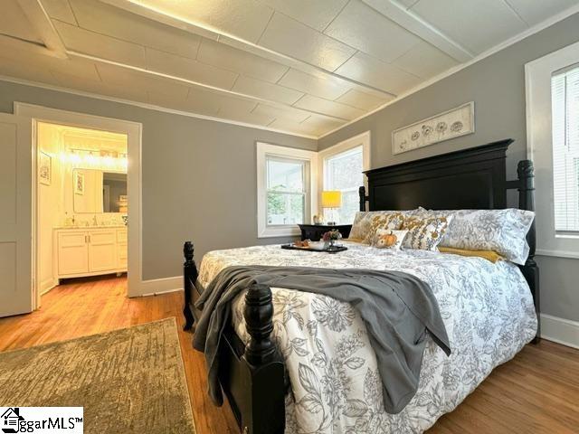 bedroom featuring ensuite bathroom, multiple windows, and light wood-type flooring