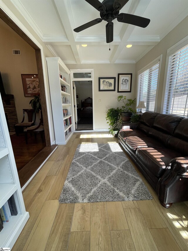 living room featuring beam ceiling, light hardwood / wood-style floors, coffered ceiling, and crown molding