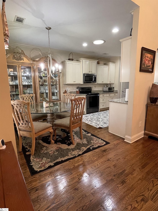 dining area featuring ornamental molding, dark wood-type flooring, and an inviting chandelier