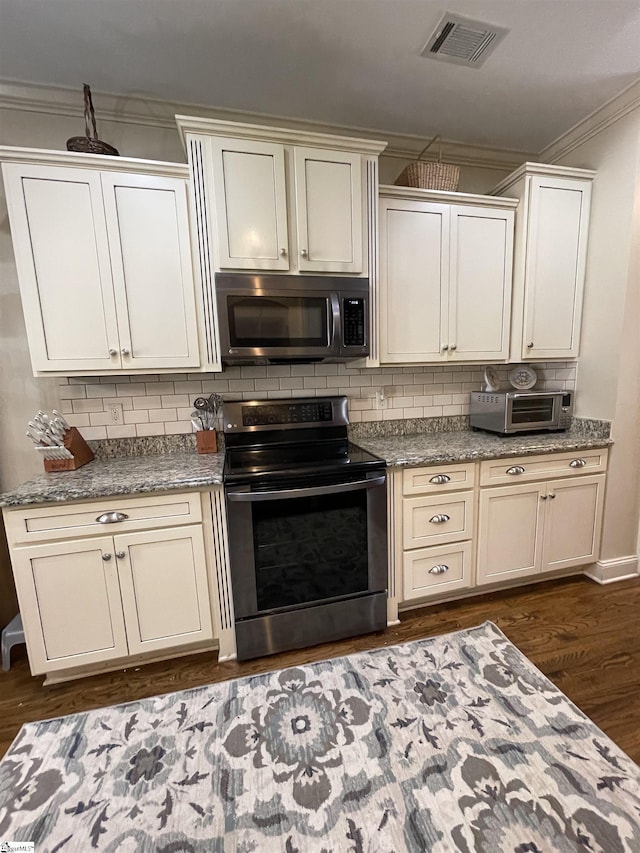 kitchen with appliances with stainless steel finishes, dark hardwood / wood-style floors, and decorative backsplash