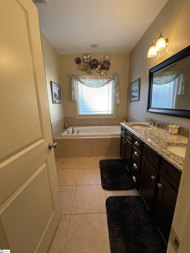 bathroom with tile patterned flooring, tiled tub, and vanity