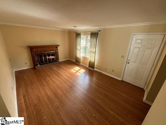 unfurnished living room with a textured ceiling, crown molding, and dark hardwood / wood-style floors