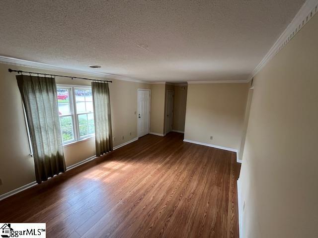 empty room featuring a textured ceiling, crown molding, and dark hardwood / wood-style flooring