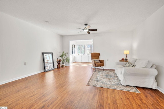 living room with a textured ceiling, ceiling fan, and light hardwood / wood-style flooring