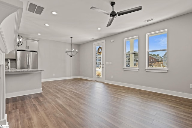 unfurnished living room with ceiling fan with notable chandelier and dark hardwood / wood-style floors