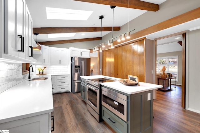 kitchen featuring appliances with stainless steel finishes, a kitchen island, white cabinetry, sink, and hanging light fixtures