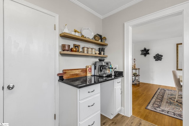 bar with white cabinets, light hardwood / wood-style floors, and crown molding