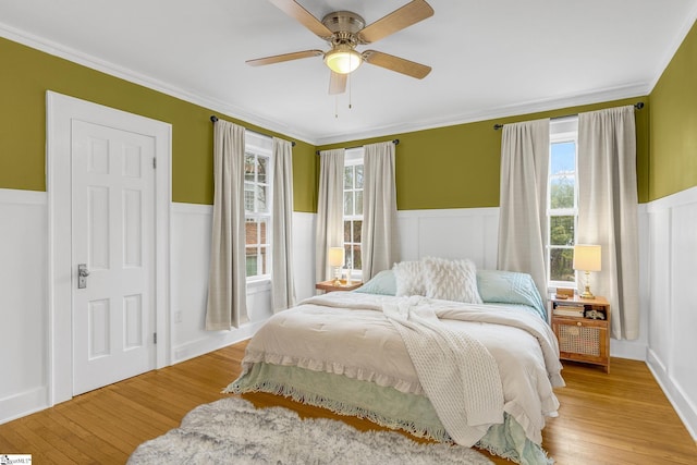 bedroom featuring ornamental molding, multiple windows, ceiling fan, and light wood-type flooring