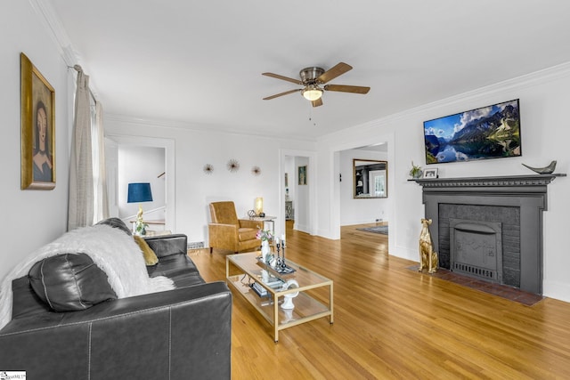 living room with wood-type flooring, ceiling fan, and crown molding