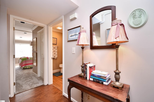 hallway featuring ornamental molding and hardwood / wood-style flooring