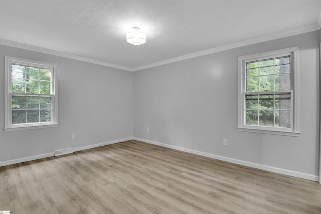 spare room with light hardwood / wood-style floors, a wealth of natural light, and crown molding