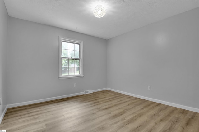 unfurnished room with a textured ceiling and light hardwood / wood-style flooring