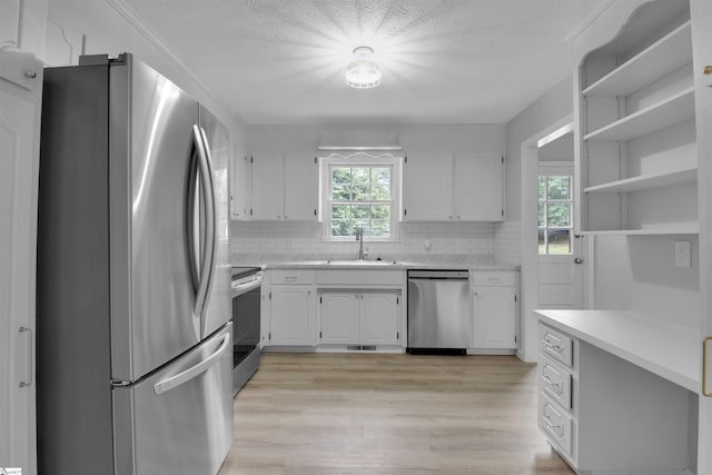 kitchen with sink, stainless steel appliances, a wealth of natural light, and white cabinetry