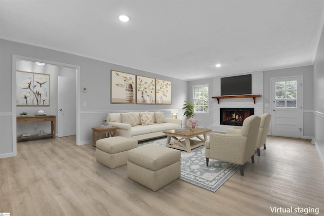 living room featuring light hardwood / wood-style floors, a brick fireplace, and a wealth of natural light