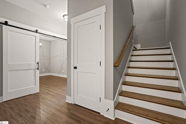 stairway with a barn door and wood-type flooring