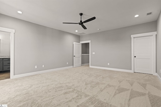 unfurnished bedroom featuring connected bathroom, ceiling fan, and light colored carpet