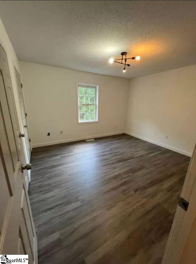 empty room featuring a textured ceiling and dark hardwood / wood-style floors